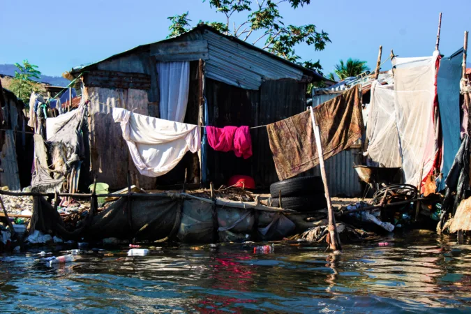 Houses built within an environment littered with debris and tires on the coast of Carrefour, reflecting the implementation of the dangerous practice "fè tè."