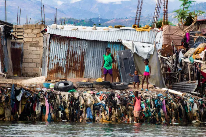 A family gathers in their courtyard on the coast of Carrefour, surrounded by tires and clutter. | © Kenley Augustin