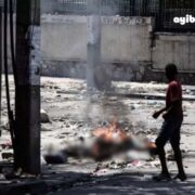 Un adolescent curieux scrute des yeux un corps calciné dans les rues de Port-au-Prince le 4 mars 2024, dans la Rue Oswald Durand, à quelques mètres du Palais national.