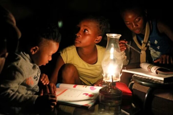 Children use a paraffin lamp to study during a blackout in Soweto © Siphiwe Sibeko/Reuters