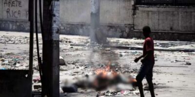 Un adolescent curieux scrute des yeux un corps calciné dans les rues de Port-au-Prince le 4 mars 2024, dans la Rue Oswald Durand, à quelques mètres du Palais national.