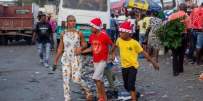 Une femme marche avec ses garçons dans une rue tout en portant des bonnets de Noël à Port-au-Prince, en Haïti, jeudi 24 décembre 2021. © Dieu Nalio Chery/AP