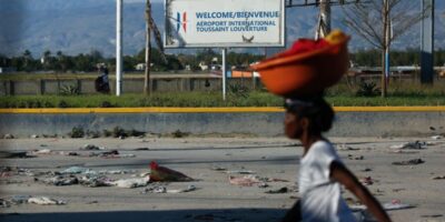 Une femme seule dans une rue déserte de Port-au-Prince, une cuvette posée sur la tête.