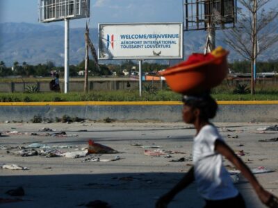 Une femme seule dans une rue déserte de Port-au-Prince, une cuvette posée sur la tête.