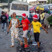 Une femme marche avec ses garçons dans une rue tout en portant des bonnets de Noël à Port-au-Prince, en Haïti, jeudi 24 décembre 2021. © Dieu Nalio Chery/AP