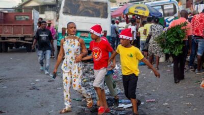 Une femme marche avec ses garçons dans une rue tout en portant des bonnets de Noël à Port-au-Prince, en Haïti, jeudi 24 décembre 2021. © Dieu Nalio Chery/AP