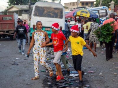 Une femme marche avec ses garçons dans une rue tout en portant des bonnets de Noël à Port-au-Prince, en Haïti, jeudi 24 décembre 2021. © Dieu Nalio Chery/AP