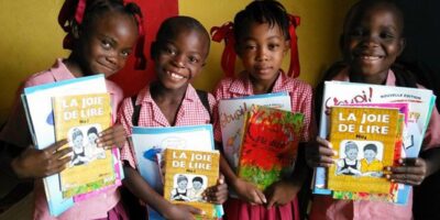 Quatre jeunes écoliers haïtiens tenant des ouvrages scolaires entre les mains.