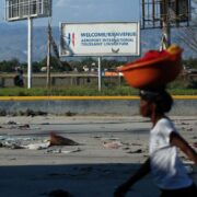 Une femme seule dans une rue déserte de Port-au-Prince, une cuvette posée sur la tête.