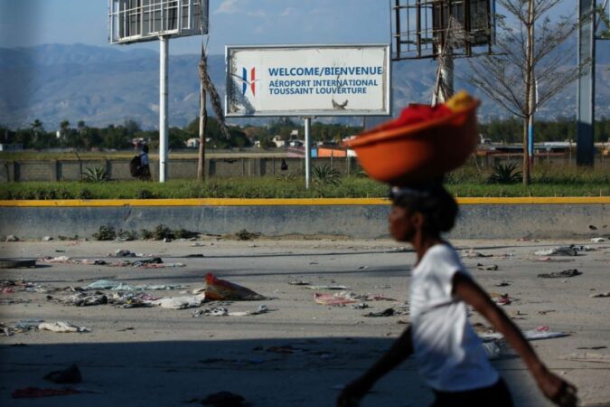 Une femme seule dans une rue déserte de Port-au-Prince, une cuvette posée sur la tête.