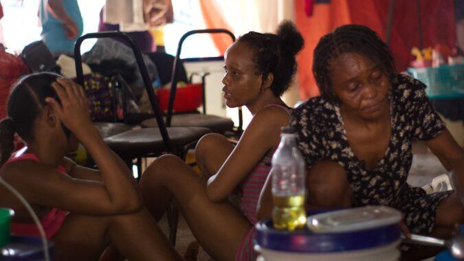 Clarena Jean Philippe on the left and Claudine Jean Philippe in the middle, accompanied by their aunt Roselie Louissaint on the right, housed at the Office de la Protection du Citoyen (OPC) camp in May 2025.