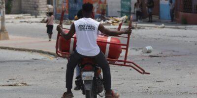 Un homme transporte une bouteille de gaz parmi les objets récupérés chez lui après le passage des gangs à Solino, le XY août 2025. Photo : Jean Feguens Regala / AyiboPost