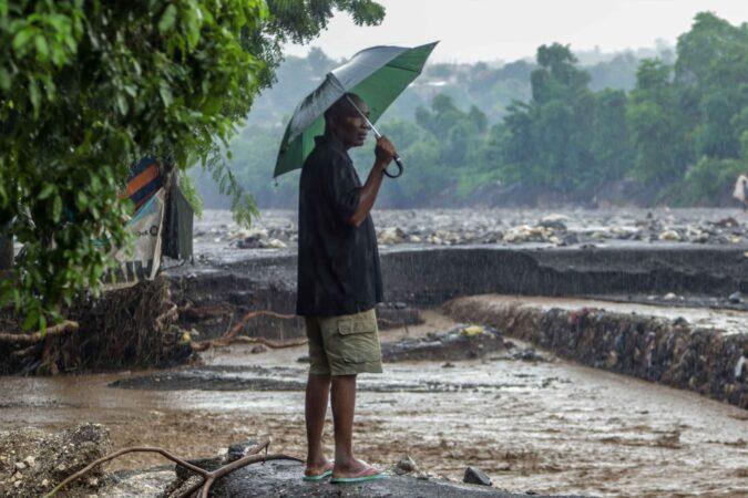 Un homme observe le débordement de la rivière La Digue, qui emporte une partie de sa berge. Vendredi 31 octobre 2025. | © Jean Feguens Regala / AyiboPost