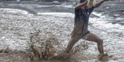 Un homme lutte contre les eaux déferlantes de la rivière La Digue pour rejoindre la douzième section de Petit-Goâve. Vendredi 31 octobre 2025. | © Jean Feguens Regala / AyiboPost