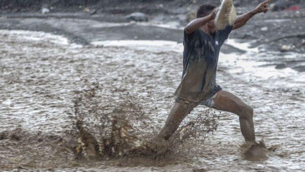 Un homme lutte contre les eaux déferlantes de la rivière La Digue pour rejoindre la douzième section de Petit-Goâve. Vendredi 31 octobre 2025. | © Jean Feguens Regala / AyiboPost
