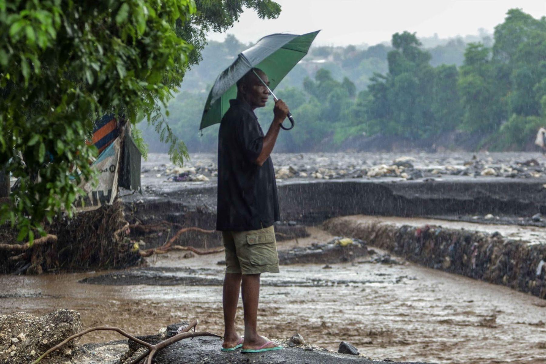 Un homme observe le débordement de la rivière La Digue, qui emporte une partie de sa berge. Vendredi 31 octobre 2025. | © Jean Feguens Regala / AyiboPost